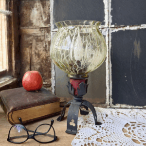 Vintage Tischlampe mit Glas und Gusseisenfuß im rustikalen Stil, gefertigt vermutlich in der DDR. Die Leuchte kombiniert bernsteinfarbenes Glas mit einem ornamentierten Gusseisenfuß. Modell „Lunaria“, ca. 30 cm hoch, mit 200 cm Kabel und E14-Fassung. Funktionstüchtig, mit leichten Altersmerkmalen – ein poetischer Lichtblick vergangener Tage