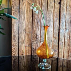 Vintage mundgeblasene Vase aus Thüringen in bernsteinfarbener Glasur, ca. 22 cm hoch, mit feinem, handgezogenem Hals und leicht asymmetrischer Tropfenform. Typisches Studioglas aus der Region Lauscha, 1950er–70er Jahre. Lufteinschlüsse und Glanz als Zeichen echter Handarbeit – ideal als Einzelstück im Wabi-Sabi-Stil.